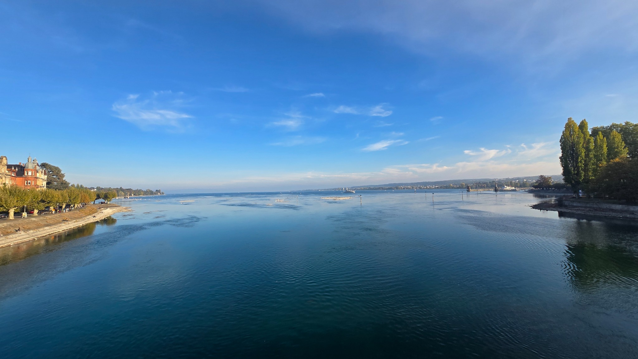 Weiter Blick über den Bodensee bei Konstanz mit Ufer und blauem Himmel